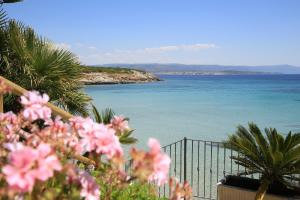 a view of the ocean from a balcony with pink flowers at Hotel Punta Negra in Alghero