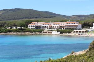 a large building on a beach next to the water at Hotel Punta Negra in Alghero