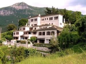 a large house on a hill with a mountain in the background at Hotel Taxiarches in Aristi