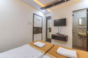 a bedroom with a bed and a television and a sink at Hotel Nest Inn in Mumbai