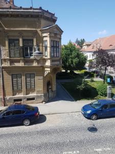 dos autos estacionados en una calle frente a un edificio en Schiller Apartments, en Sibiu
