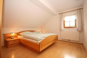 1 dormitorio con cama de madera y ventana en Appartement Steinacher, en Schladming