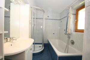 ein Badezimmer mit einem Waschbecken, einer Badewanne und einer Dusche in der Unterkunft Appartement Steinacher in Schladming