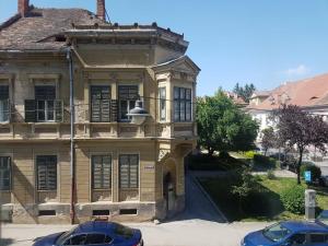 una casa vieja con dos coches aparcados delante en Schiller Apartments, en Sibiu