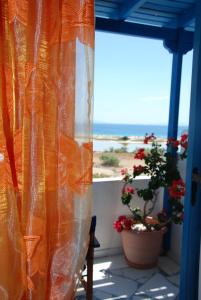 an orange curtain on a balcony with a view of the ocean at Koulas Pension - Red Lake in Agios Prokopios