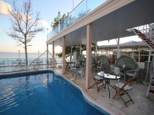 a swimming pool with tables and chairs next to the ocean at Ucem Hotel Golden Sea in Altınoluk