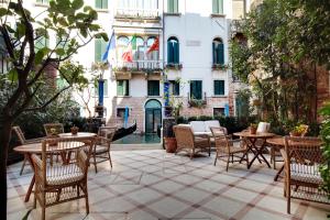 un patio avec des tables et des chaises et un bâtiment dans l'établissement Hotel Donà Palace, à Venise