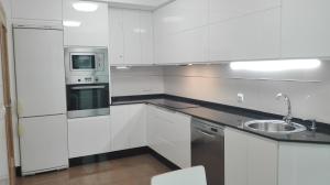 eine weiße Küche mit einer Spüle und einer Mikrowelle in der Unterkunft Apartamento Villa Clarita in Sanxenxo