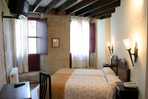 1 dormitorio con cama, mesa y ventanas en Hotel O Portelo Rural, en Allariz
