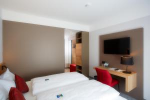 a hotel room with two beds and a desk and a television at Hotel & Restaurant Wilder Mann in Aalen