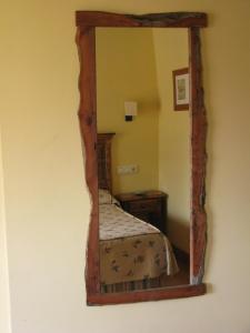 a mirror on a wall with a bed in a room at La Posada de Cucayo in Dobres