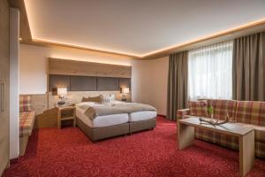 a hotel room with a bed and a desk and a couch at Hotel Andreas Hofer in Kufstein