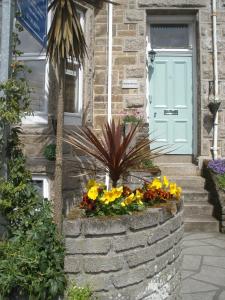 a retaining wall with flowers in front of a house at Penmorvah in Penzance