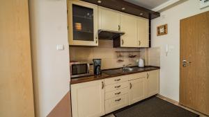 a small kitchen with white cabinets and a microwave at Ana tour in Międzyzdroje