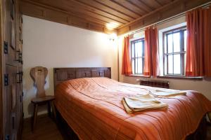 a bedroom with a bed with orange sheets and windows at Guest House Dimcho Kehaia's Cafe in Zheravna