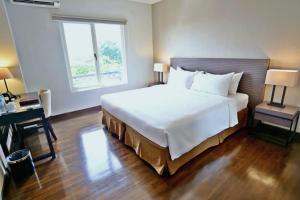 a bedroom with a large white bed and a desk at Samala Hotel Jakarta Cengkareng in Jakarta