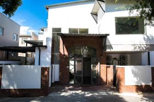 a white house with a brick doorway and a brick wall at Zeederberg Corner in Paarl
