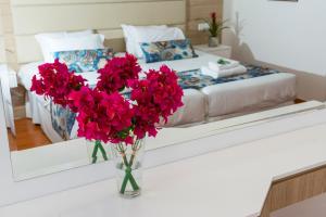 a vase with red flowers on a table in a bedroom at Ascos Coral Beach Hotel in Coral Bay