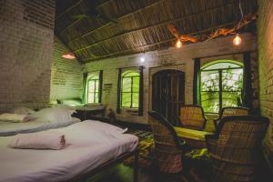 a room with two beds and chairs and windows at Shannu's Ranch Inn in Pushkar