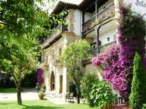 un edificio con flores púrpuras a su lado en Hotel Museo Los Infantes, en Santillana del Mar