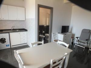 uma cozinha com uma mesa e cadeiras brancas e um lavatório em Villa Nonna Pina em Castelvetrano Selinunte