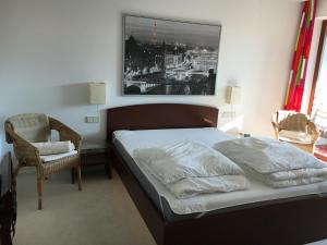 1 dormitorio con 1 cama, 1 silla y 1 foto en An den Isarauen, en Grünwald