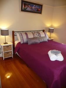 a purple bed in a bedroom with two lamps at Shepp Central Apartment in Shepparton