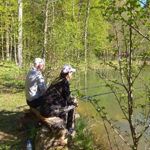 a man and a woman fishing in a pond at Pihtoviy Bor Hotel in Dakhovskaya