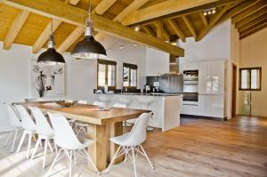 cocina y comedor con mesa de madera y sillas blancas en Apartment Fortuna 5.5 - GriwaRent AG en Grindelwald