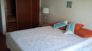 um quarto com uma cama com almofadas laranja e azul em Vacaciones en el paraíso em Lagoa