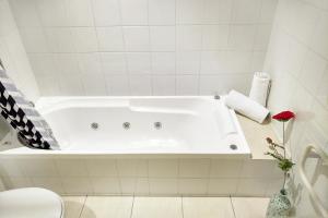 a white bath tub in a white tiled bathroom at Goldfield Holiday Home in Queenstown +20 photos