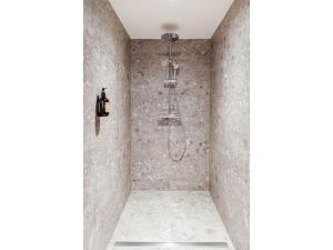 La salle de bains est pourvue d'une douche et d'un mur en pierre. dans l'établissement Goldvogel Apartments, à Fischen im Allgäu
