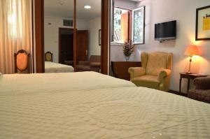 Una habitación de hotel con una cama grande y una silla. en Hotel Museo Los Infantes, en Santillana del Mar