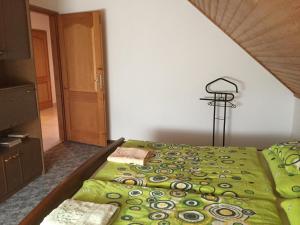 a bedroom with a green comforter on a bed at Baranya Apartman in Áta