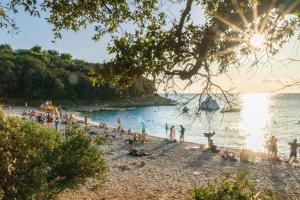 eine Gruppe von Menschen an einem Strand in der Nähe des Wassers in der Unterkunft Cosy apartment Zupanic in Pula