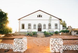 une maison blanche avec un tas de rochers devant elle dans l'établissement White House Guest Farm, à Grünau