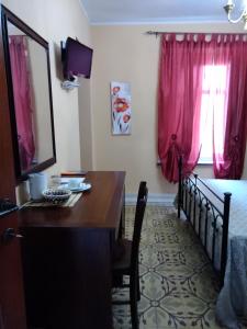 - une chambre avec une table et un lit avec des rideaux roses dans l'établissement La Corte di Lucina, à Terralba