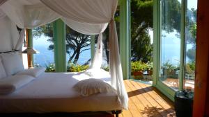 Bett in einem Zimmer mit einem großen Fenster in der Unterkunft La Casa nel Bosco in Capri