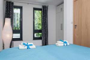 a bedroom with a blue bed with towels and bows at Nautilus Apartamenty in Rewal