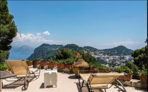 eine Terrasse mit Stühlen und Stadtblick in der Unterkunft La Casa nel Bosco in Capri