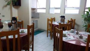 a dining room with tables and chairs and windows at Hotel Sao Nicolau in Taubaté