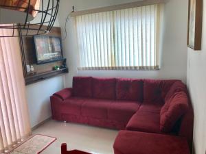 un sofá rojo en una sala de estar con ventana en Lençóis Ville Residence - CHALE 22, en Barreirinhas