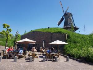 a group of people sitting at tables in front of a windmill at Kazemat Zus in Woudrichem