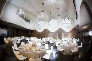 un salón de banquetes con mesas y sillas blancas y lámparas de araña en Mastinell Cava & Boutique Hotel by Olivia Hotels Collection, en Vilafranca del Penedès