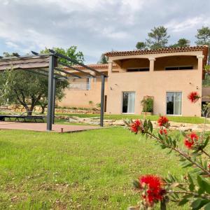 a house in a park with red flowers in the foreground at La Villa aux Oliviers in Le Val