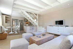 a living room with white furniture and a tv at Almondbury Cottage in Tokai