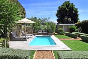 a swimming pool in a garden with an umbrella at Almondbury Cottage in Tokai