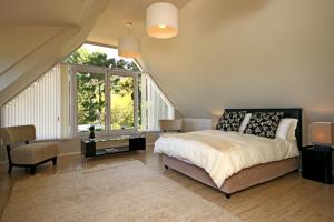 a bedroom with a bed and a large window at Almondbury Cottage in Tokai +10 photos