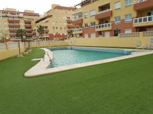 ein großer Pool mit grünem Gras und Gebäuden in der Unterkunft Apartment in South Aguadulce - Beach in Aguadulce