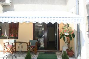 a patio with a table and a white umbrella at Pensiunea Sydney in Timişoara